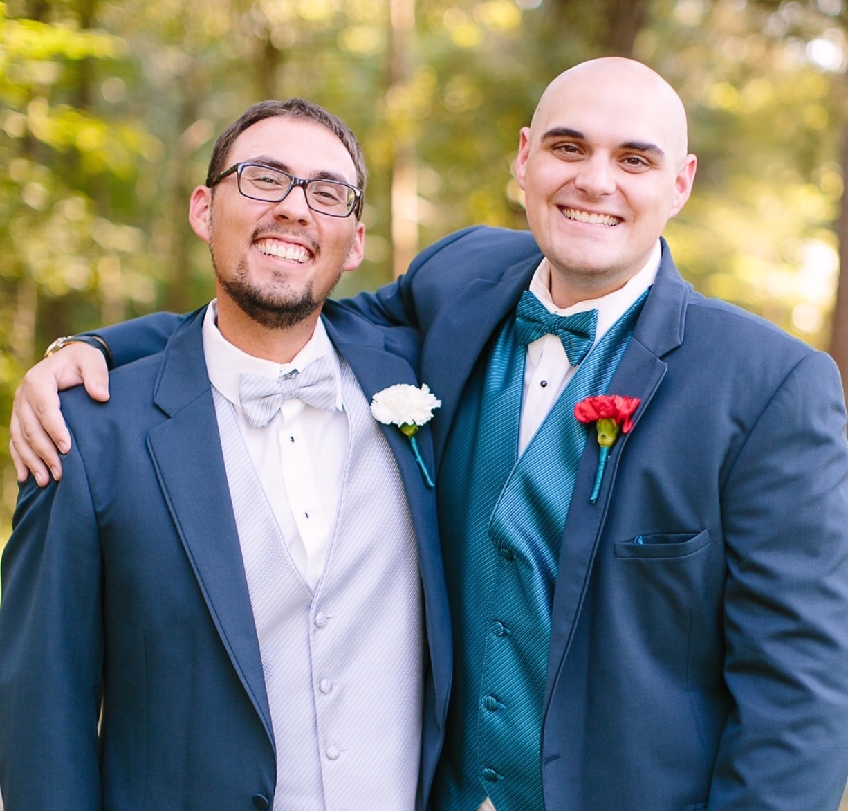 A smiling groom and groomsman embrace 