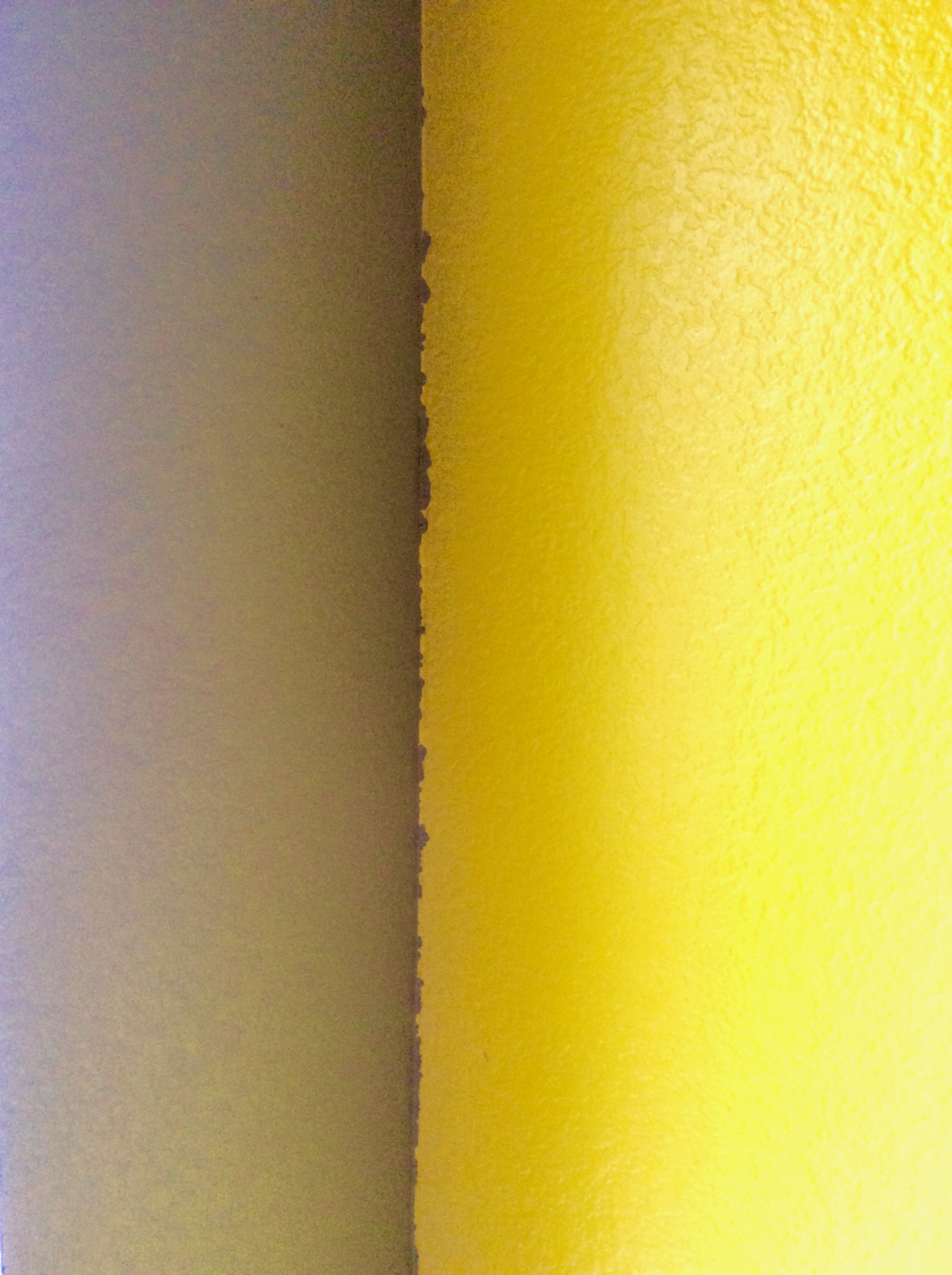 An messy paint corner where a yellow wall meets a camp green wall