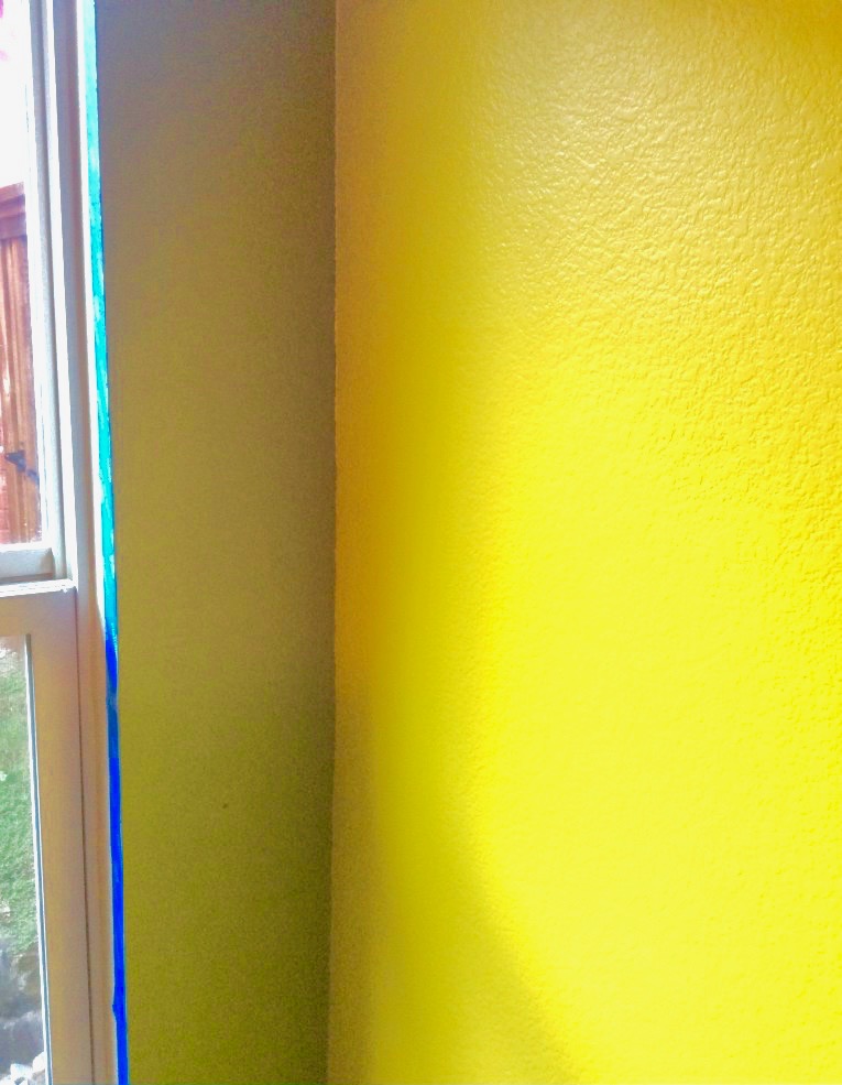 A clean painted corner where a yellow wall meets a camp green wall. 