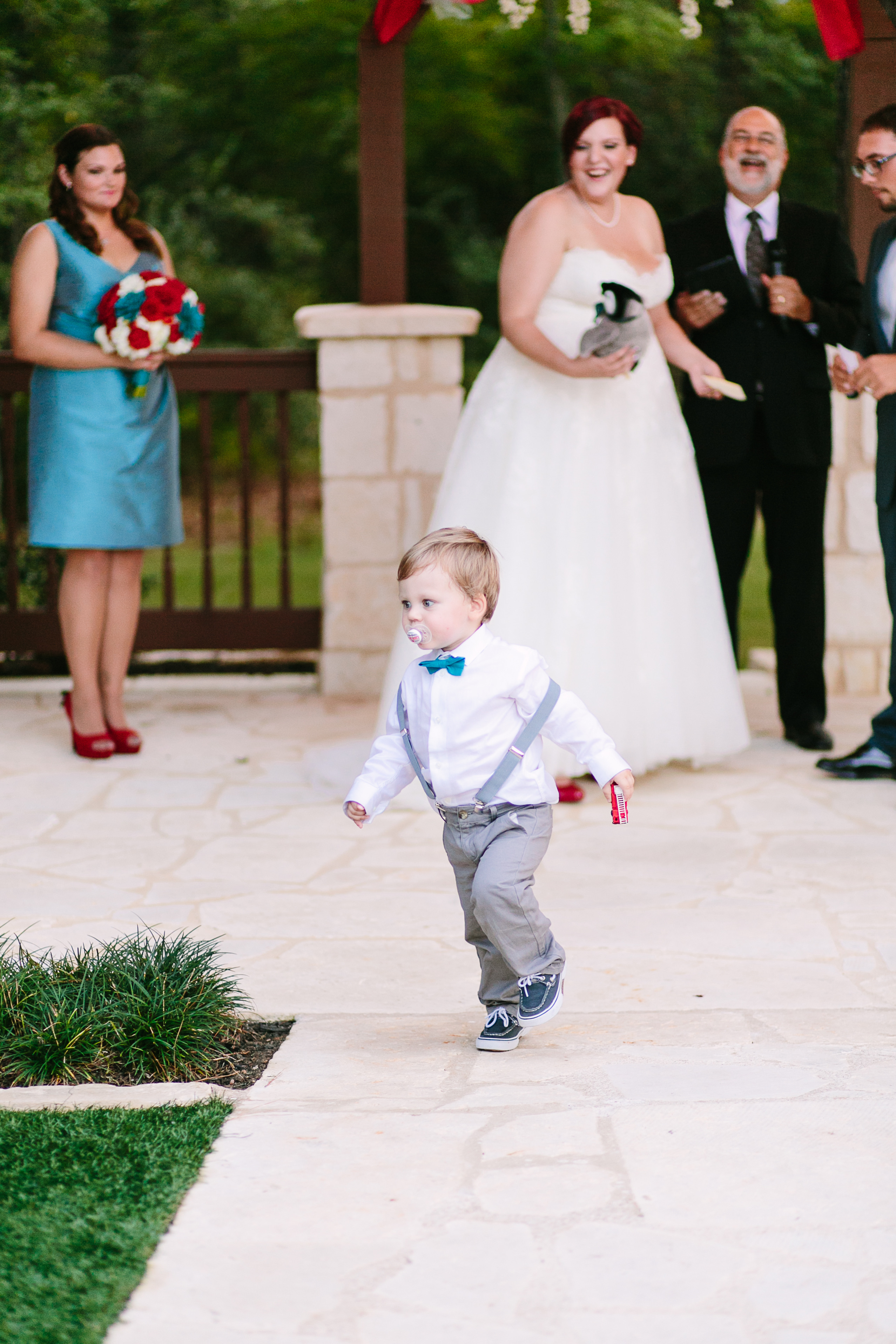 A toddler holding a fire truck runs from a wedding alter