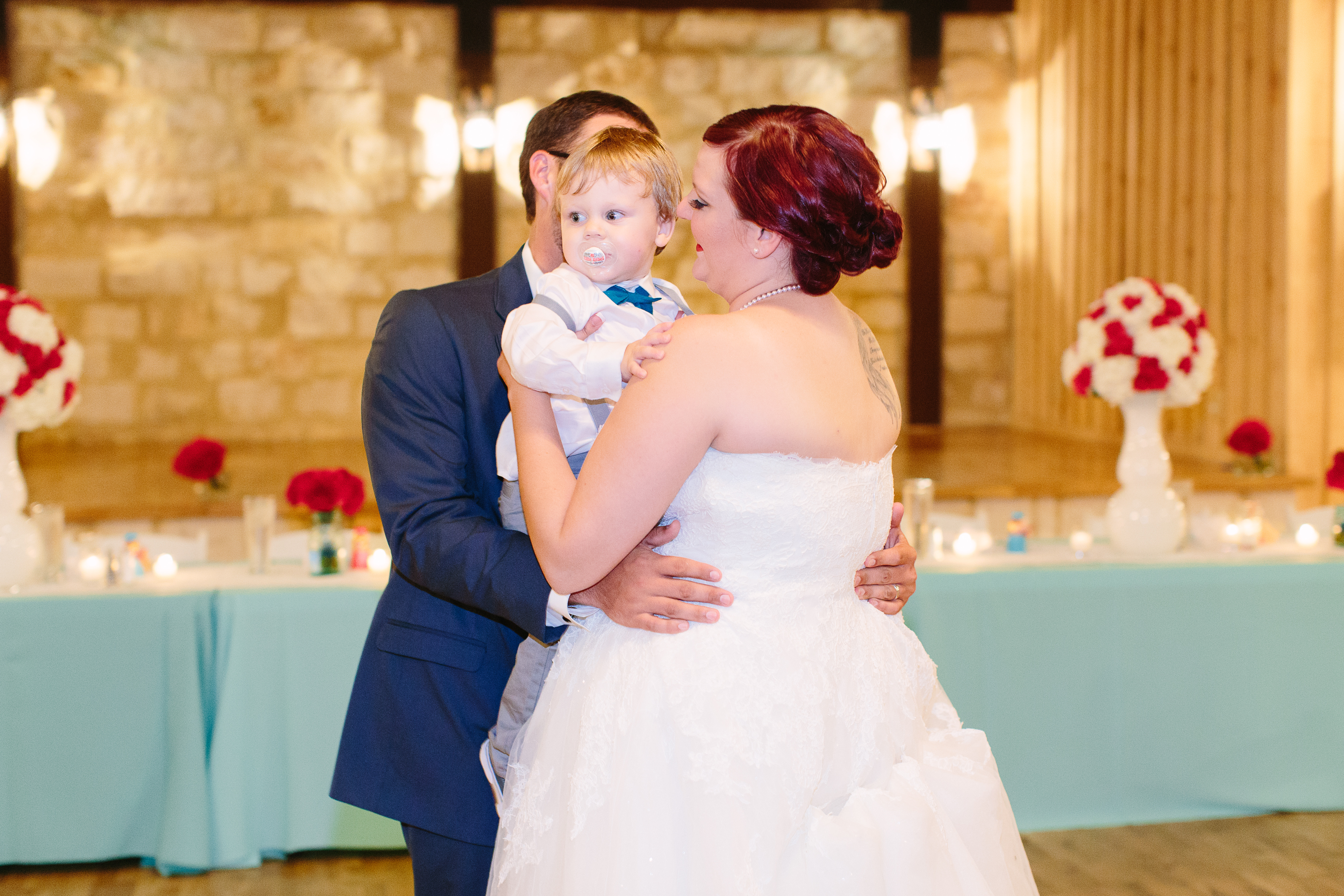 A bride and groom dance with their toddler