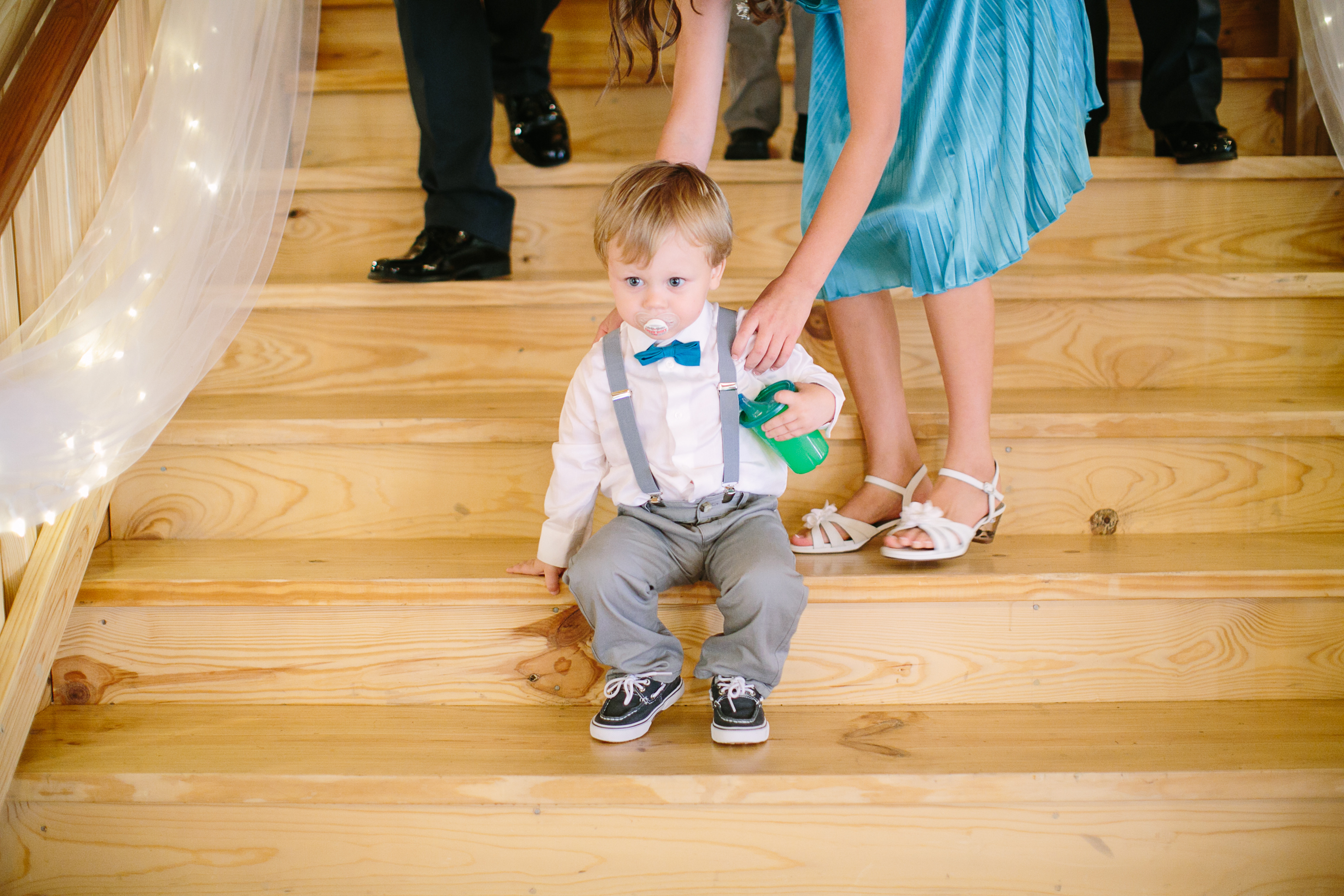 A young child sits on wood stairs in a wedding venue