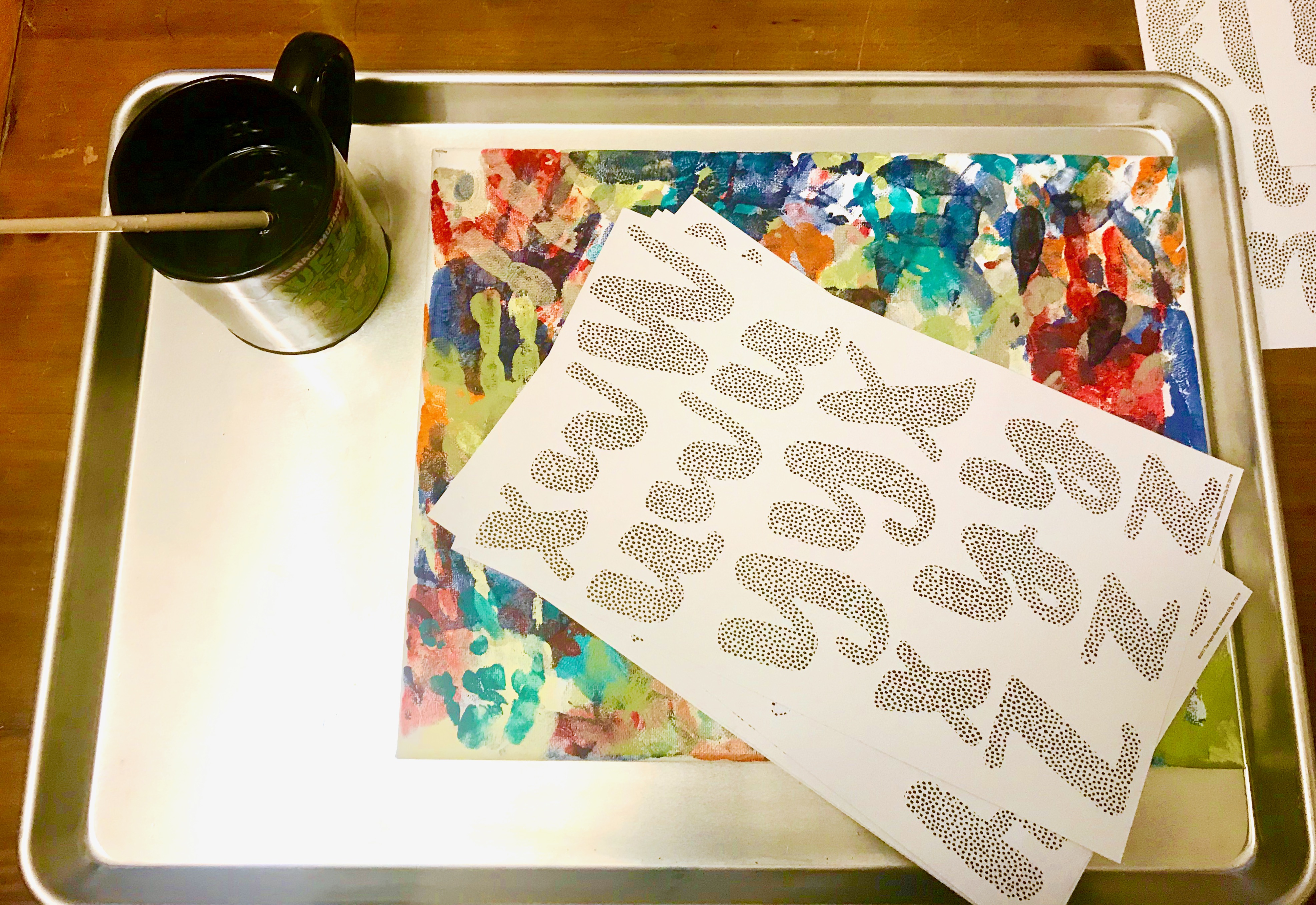 A set of letter sticker sheets on top of a canvas with paint handprints 