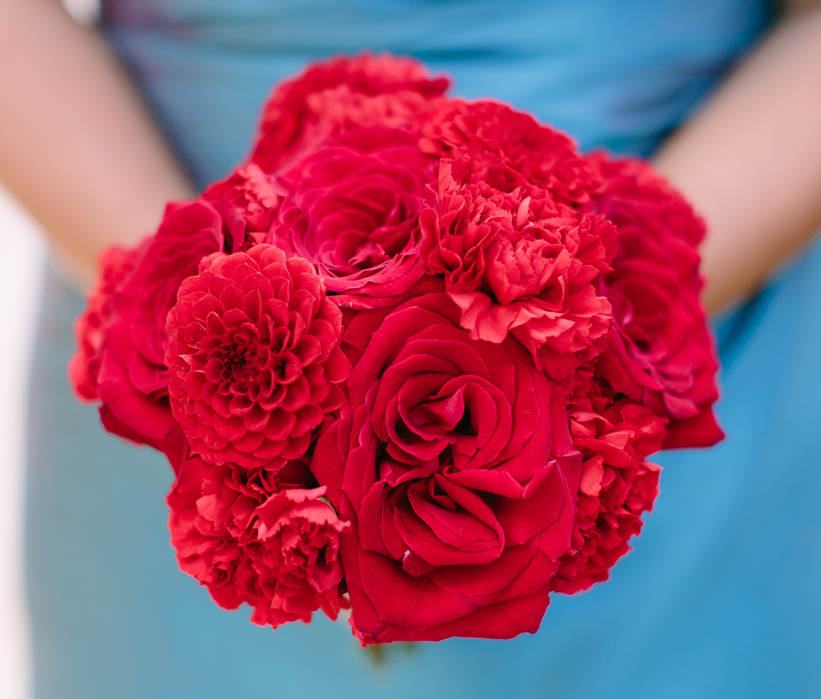 Red bridesmaid bouquet in front of a teal dress