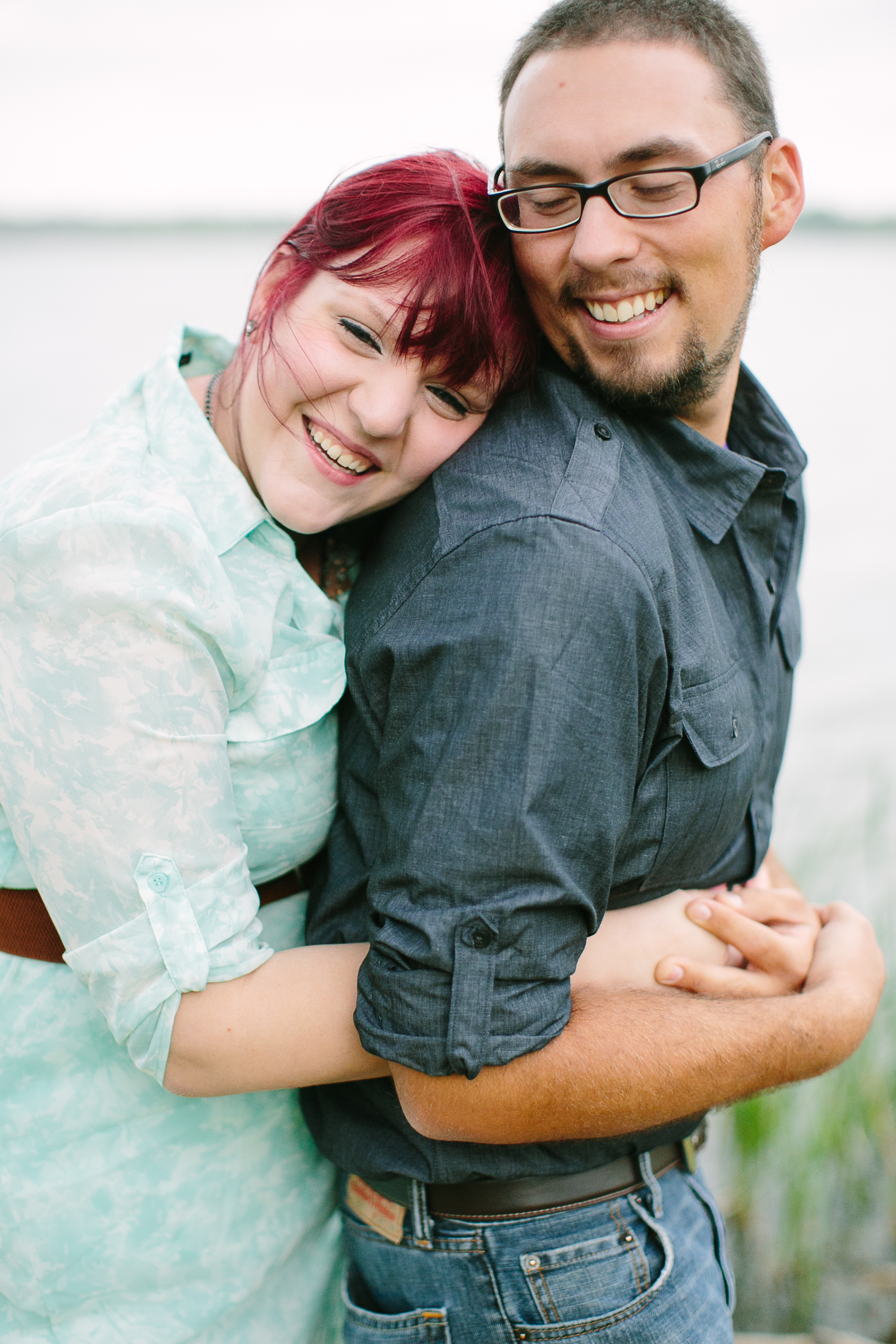 Red Headed woman in blue dress embraces a smiling man.