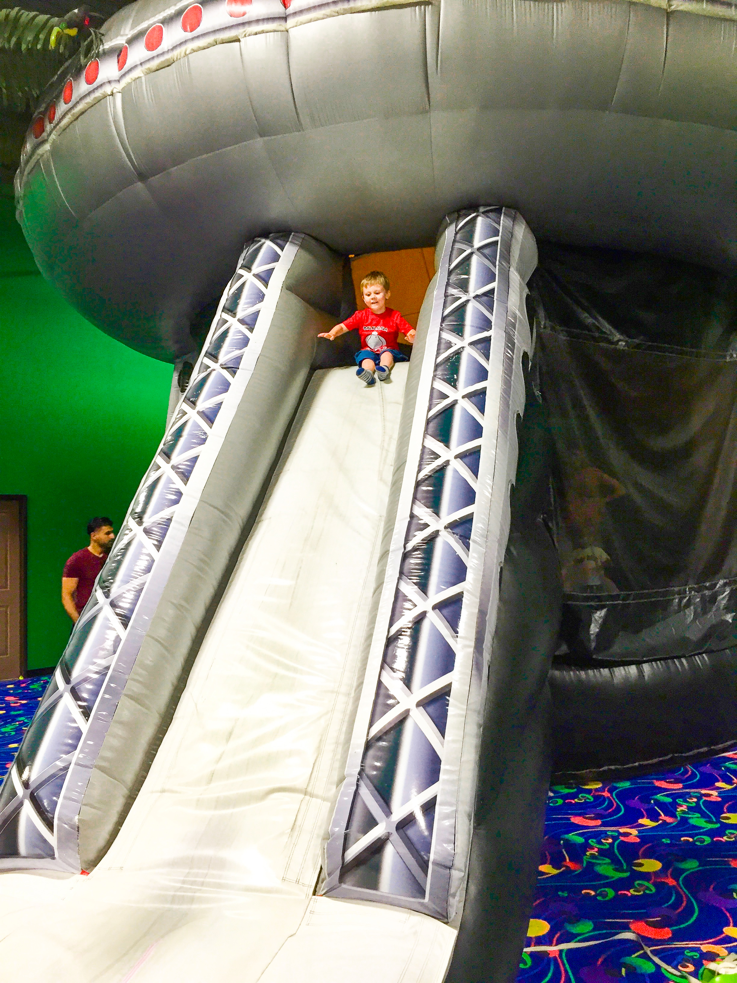 Boy on a big spaceship bouncy slide. 