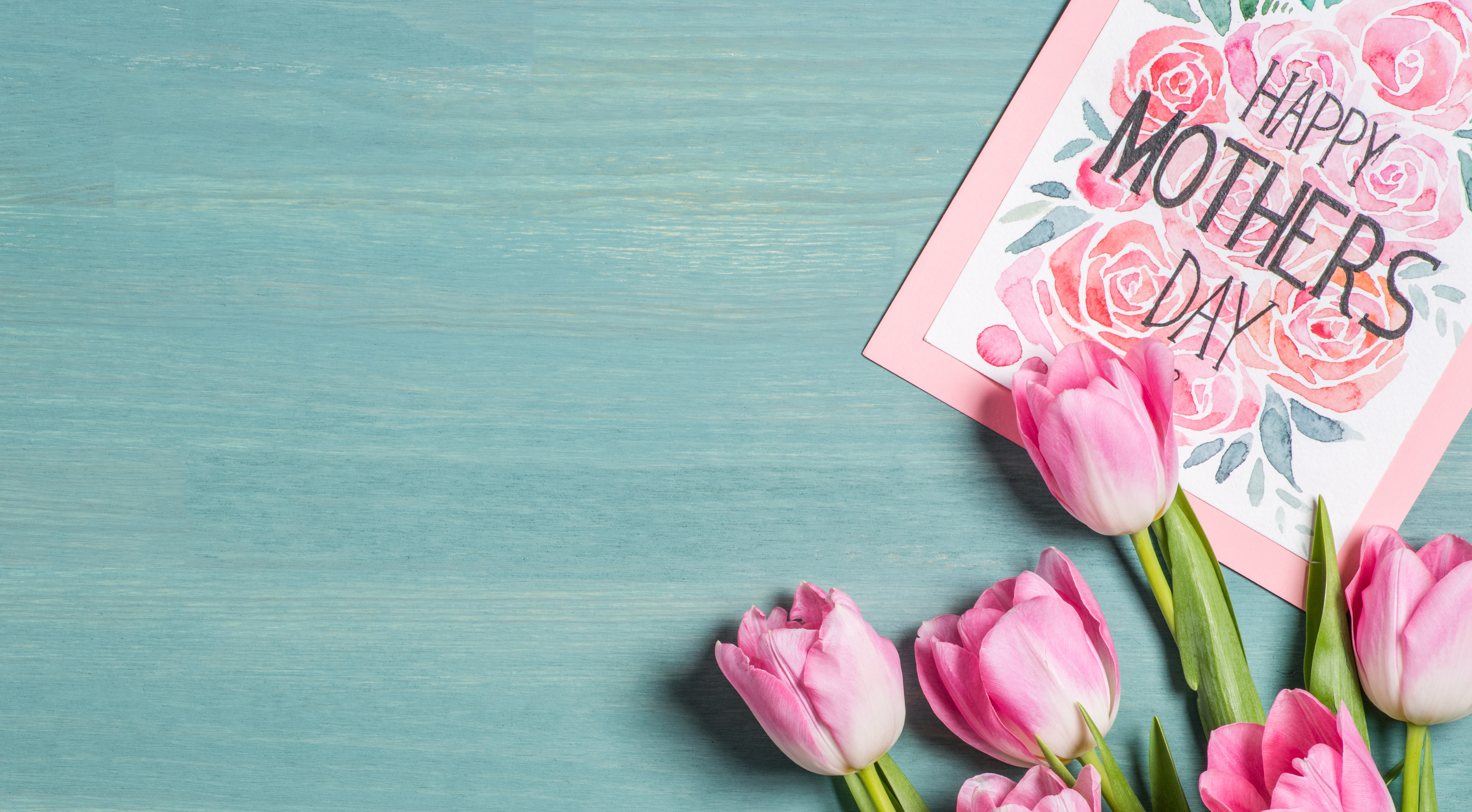 Pink tulips and a Happy mother's day card on a teal background