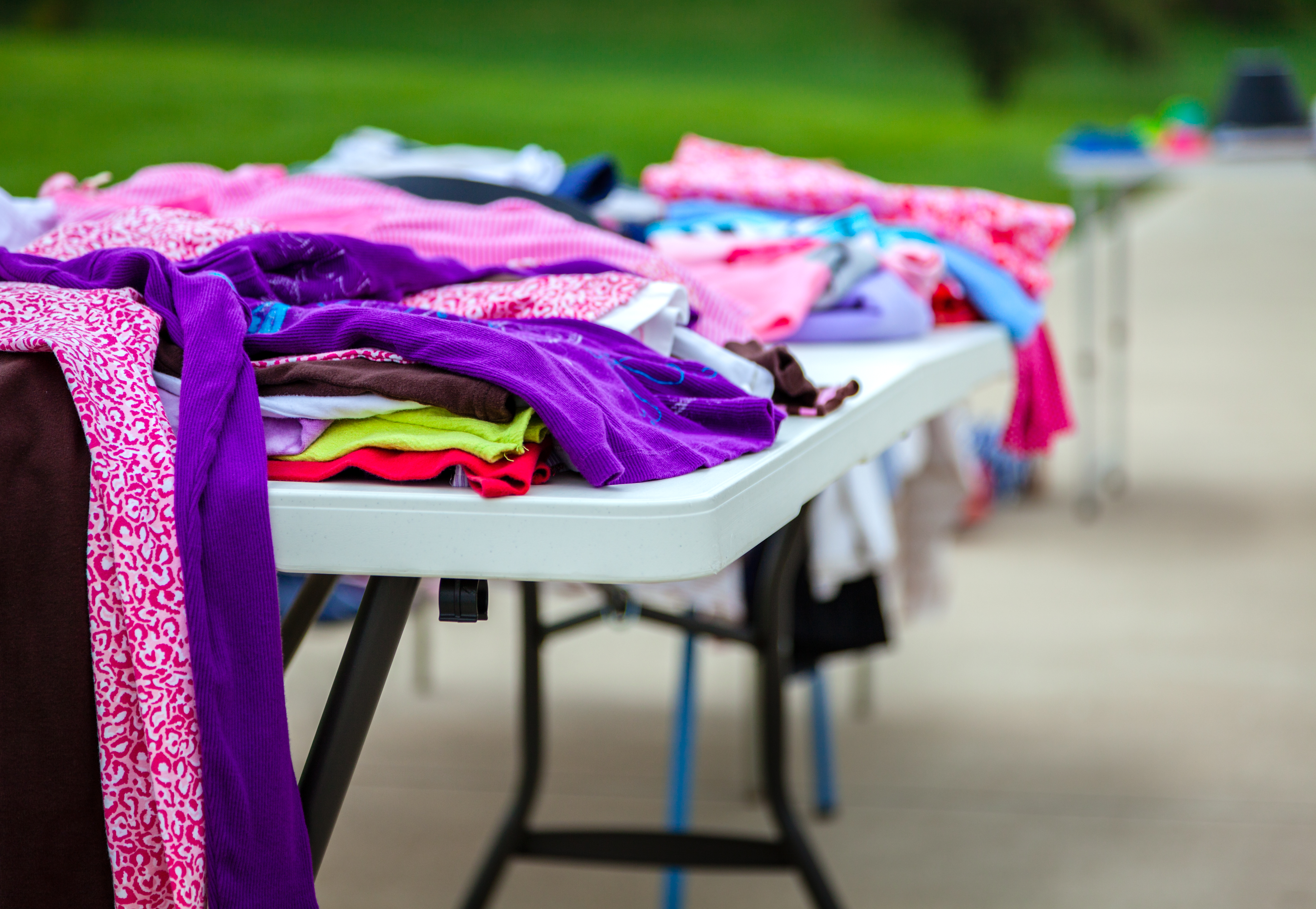 Colorful clothes displayed on a table at a garage sale