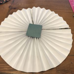 A square piece of card stock glued to the back of a paper pinwheel. 