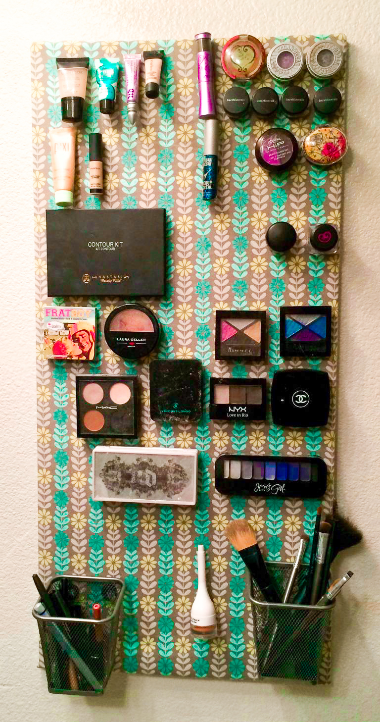 A hanging fabric wrapped magnetic board covered in a variety of make-up products.