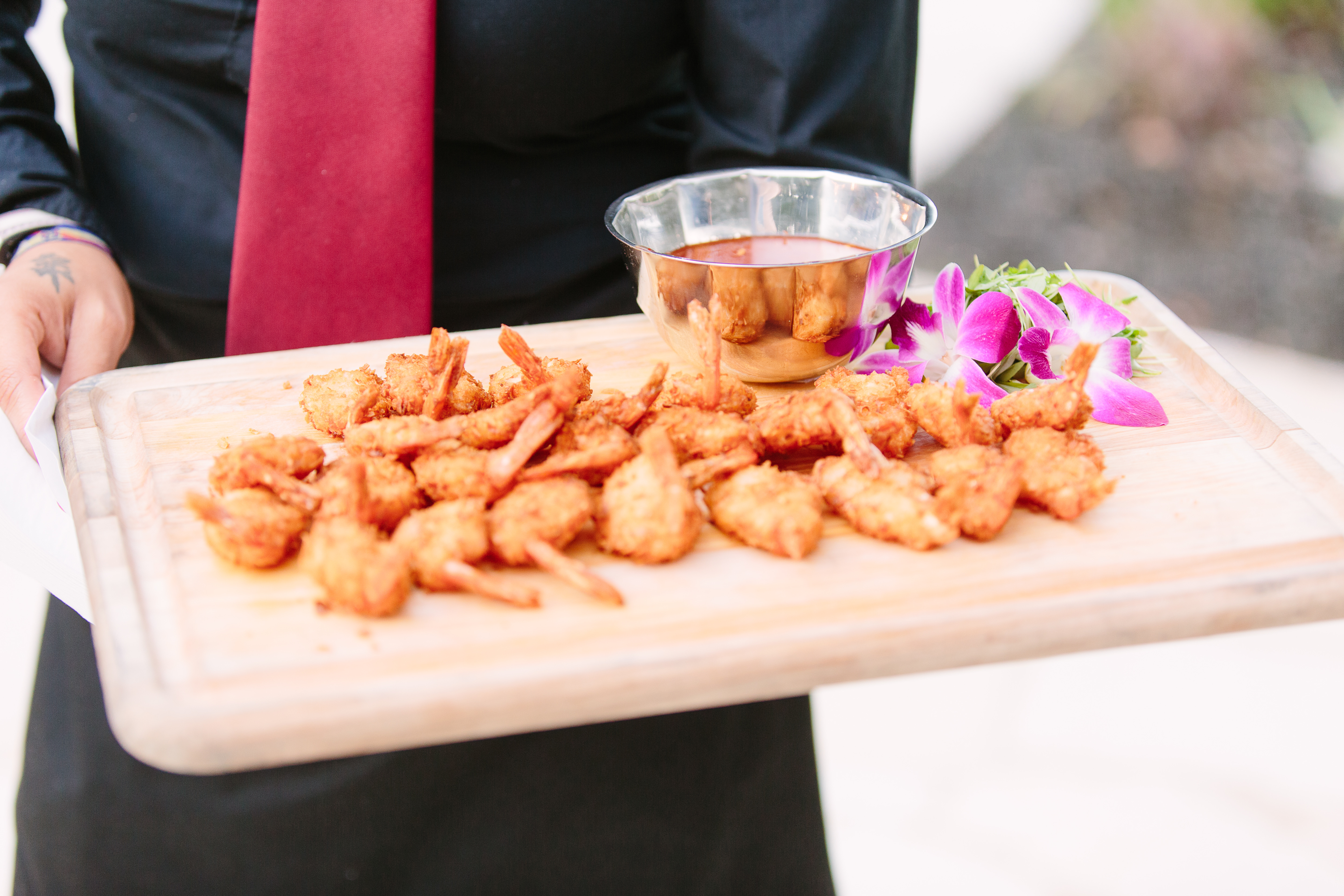 Coconut crusted shrimp and dipping sauce displayed on a wood carving board