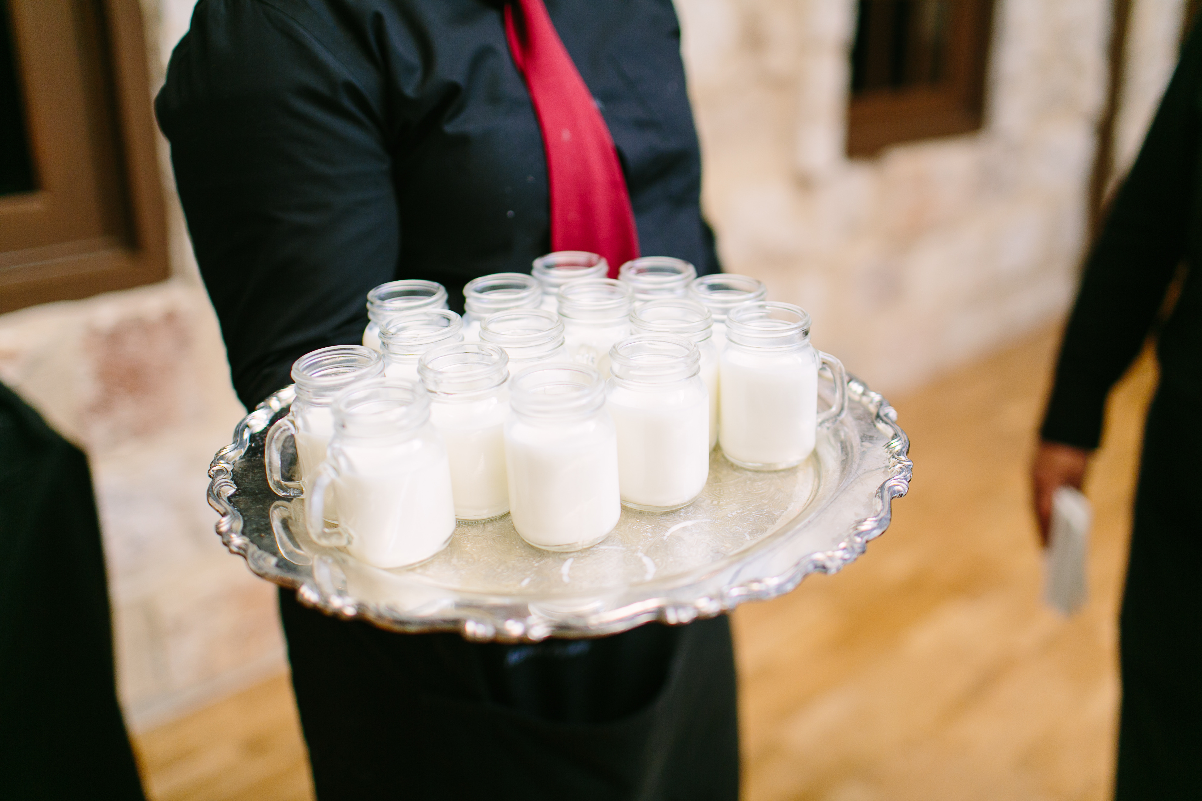 Mugs of milk on a silver platter held by a server