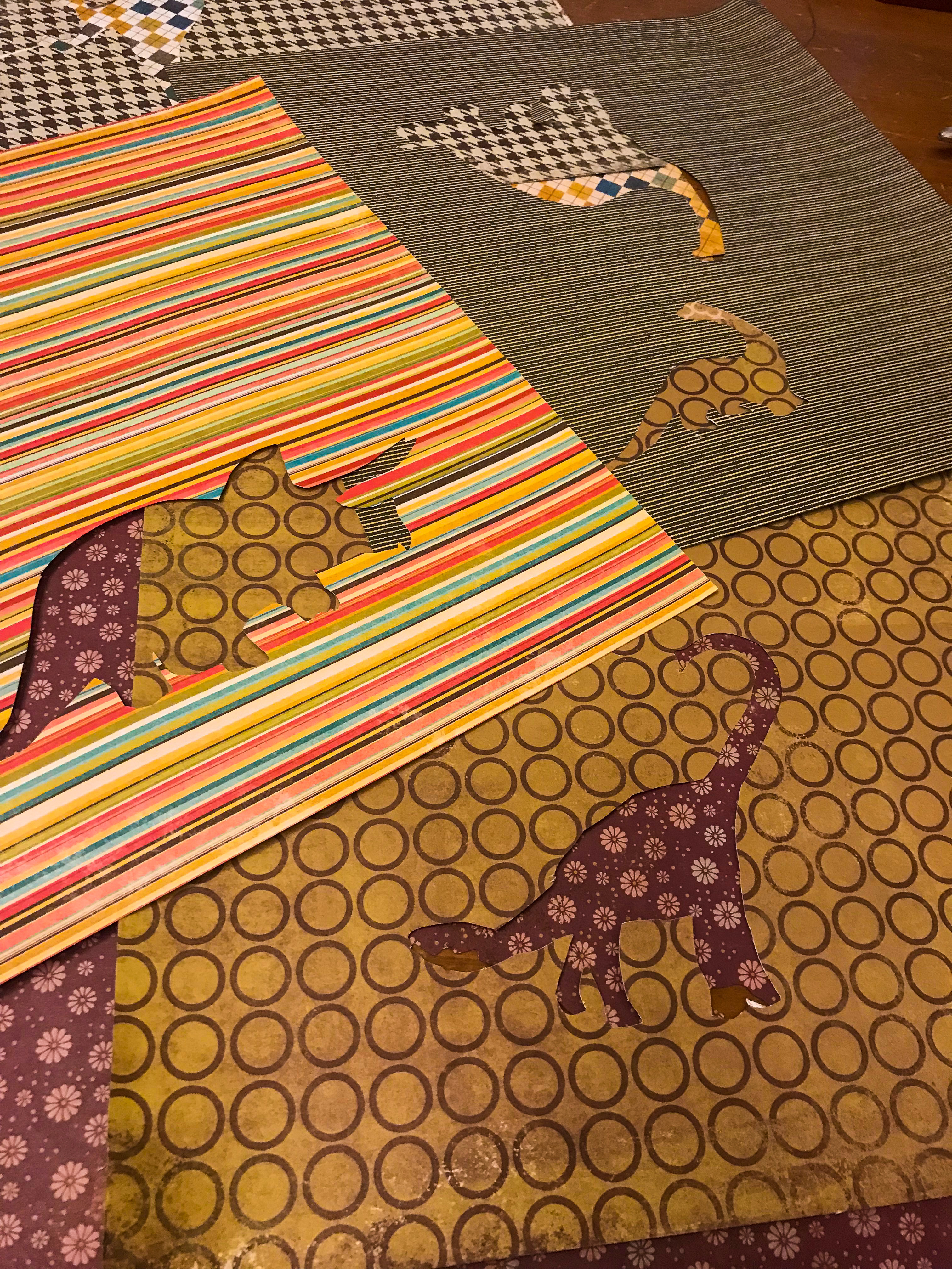 Brightly colored scrapbook paper with dinosaurs cut out. 