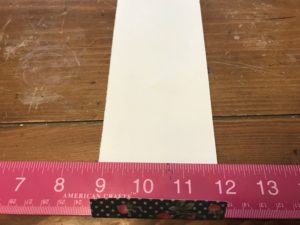 A ruler being used to make neat folds in a piece of scrapbook paper