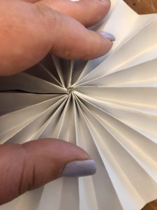 Holding the paper pinwheel flat until the hot glue dries