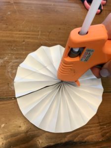 Hot glue being applied to the center of a paper pinwheel