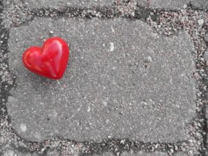 A red stone heart on a concrete paver tile