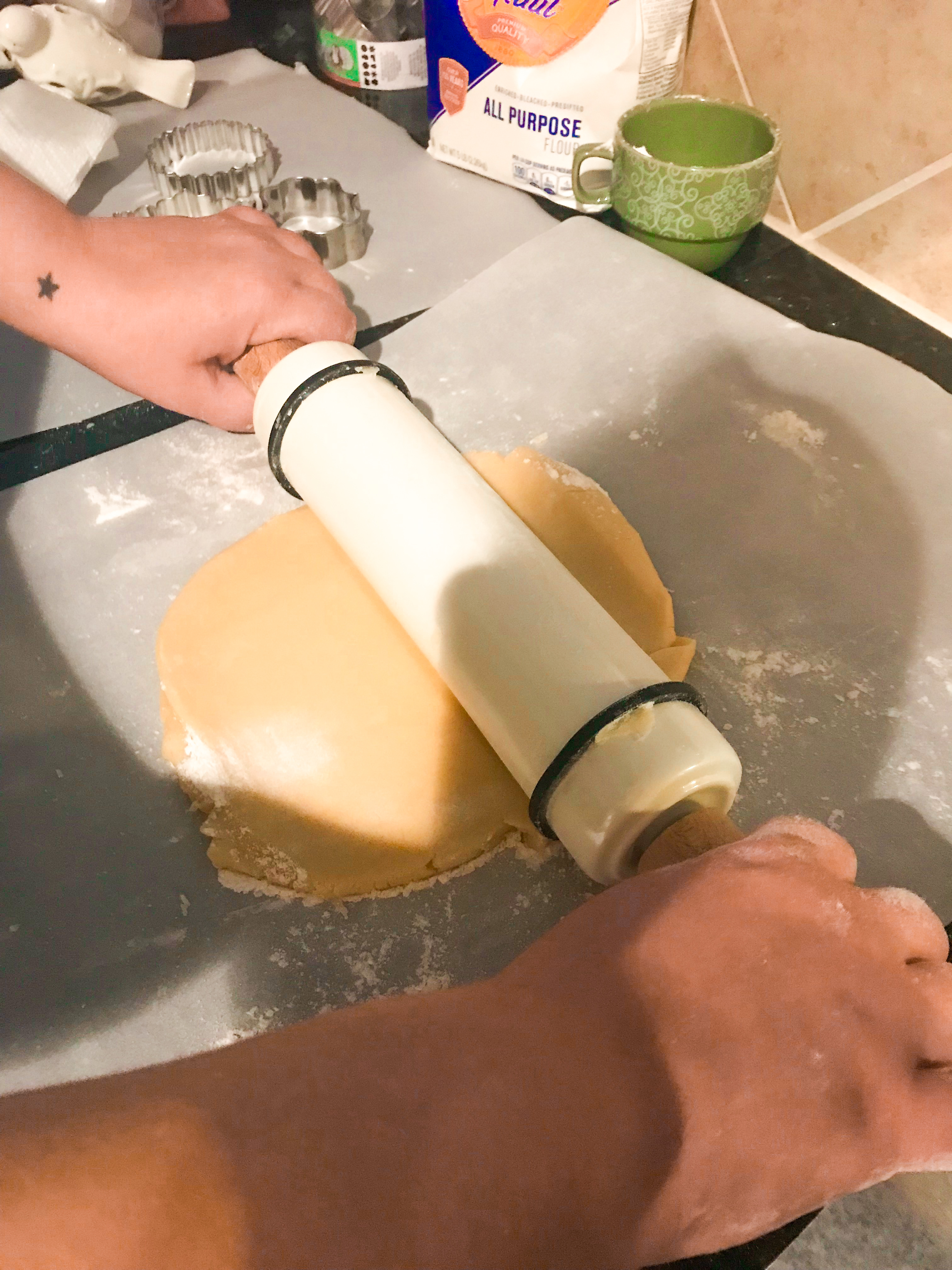 A person rolling out cookie dough with a rolling pin. 