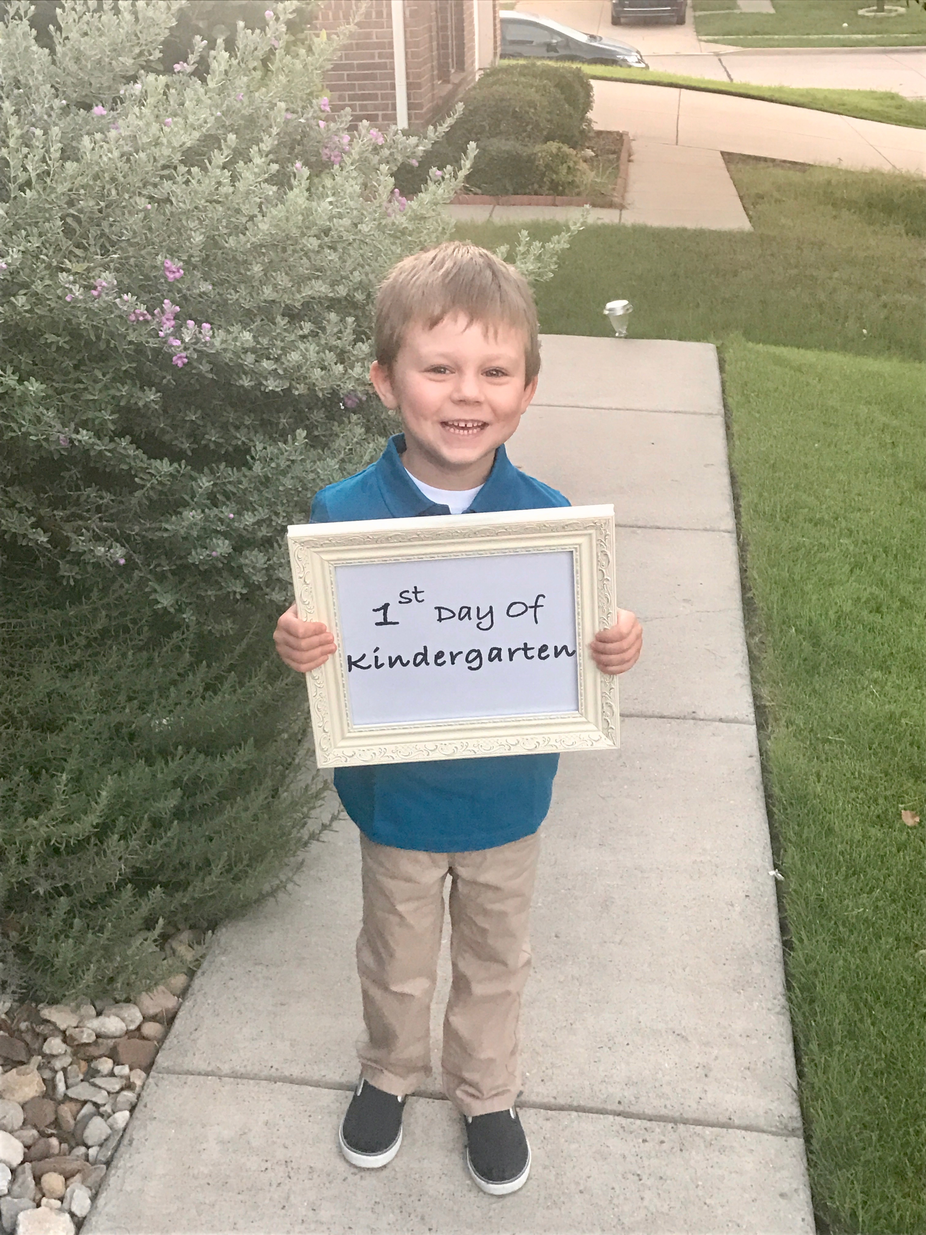 A smiling boy holding a framed back to school sign. 