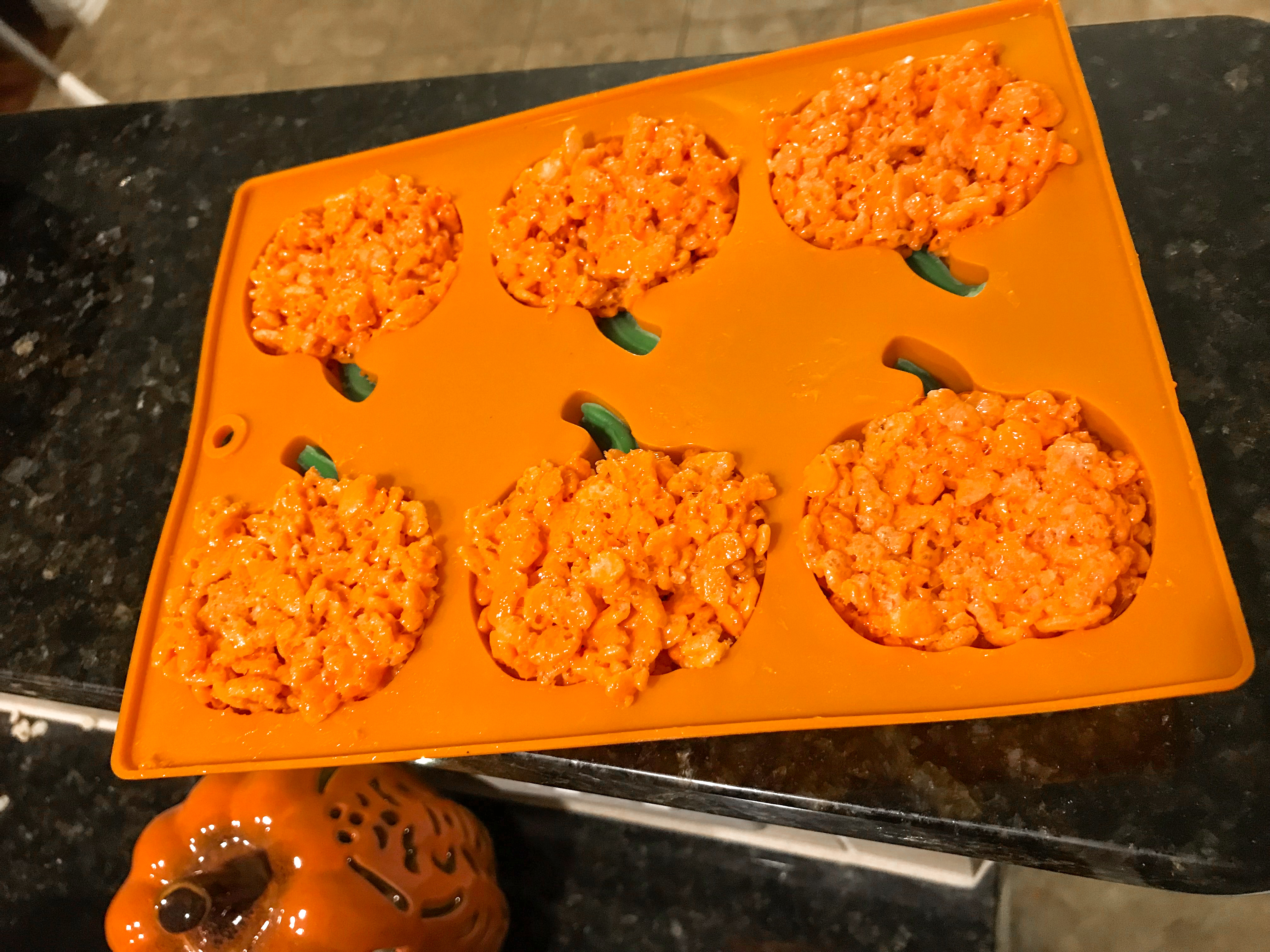 Filling a pumpkin silicone mould with rice krispie treat mix. 