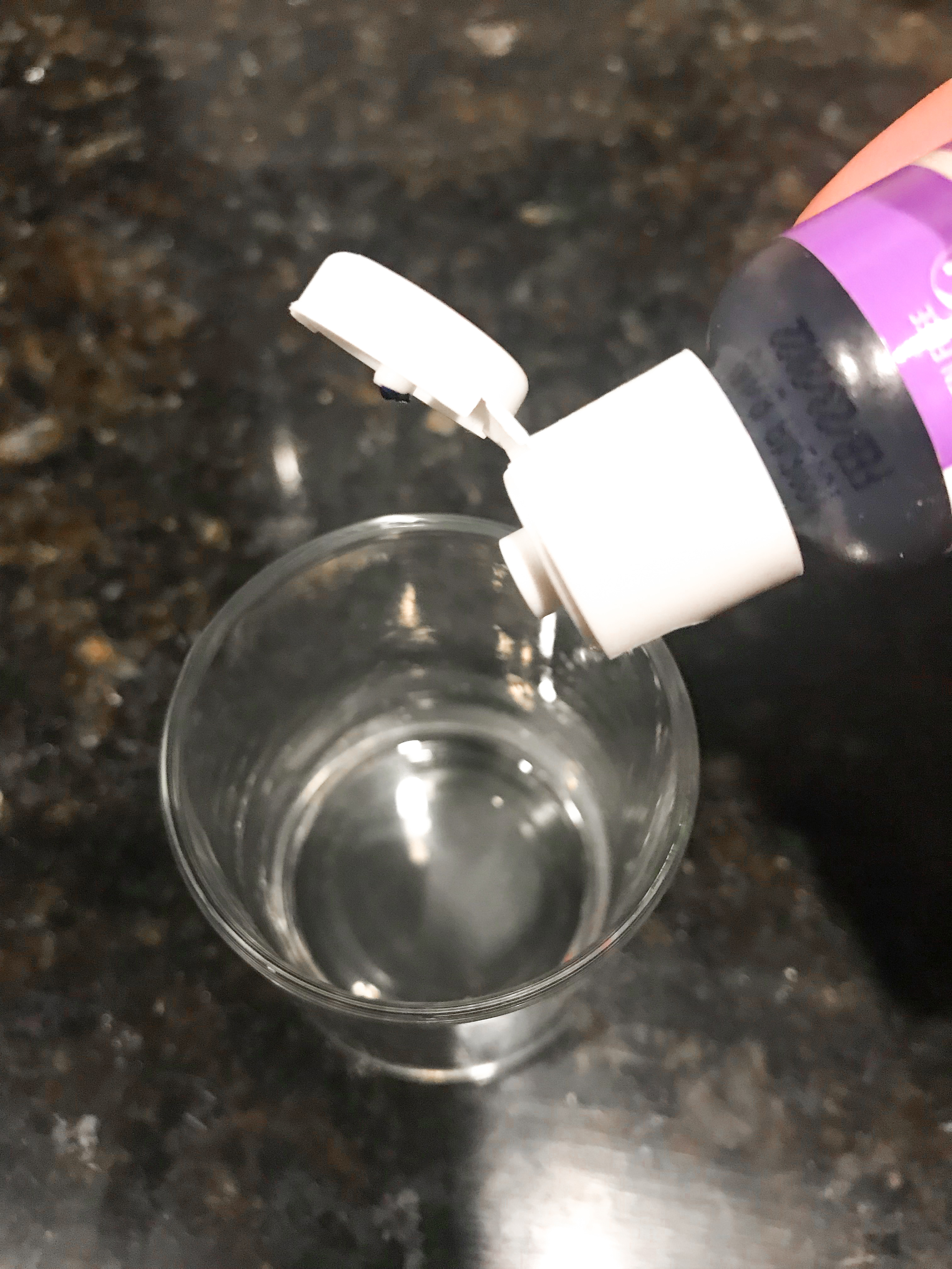 Dripping purple food coloring into vodka in a shot glass. 