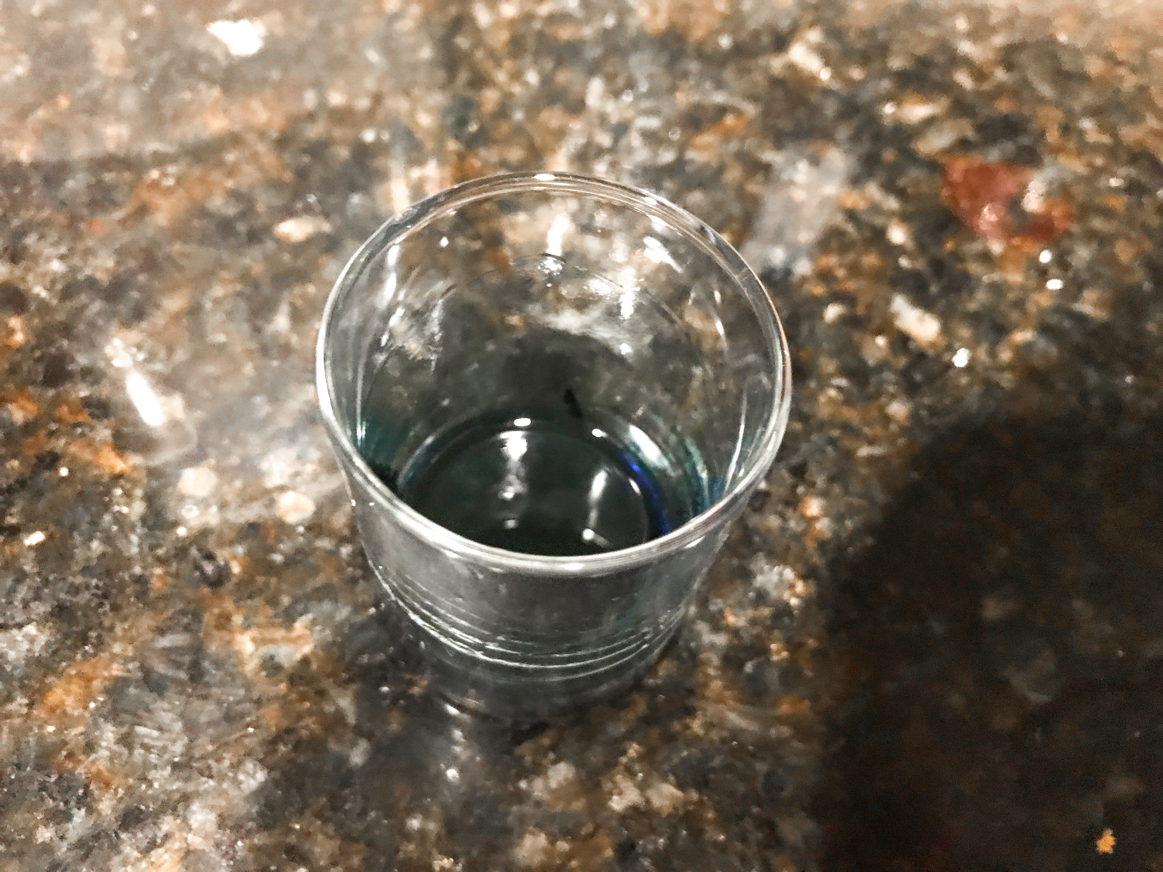 A small amount of purple colored vodka in a shot glass. 