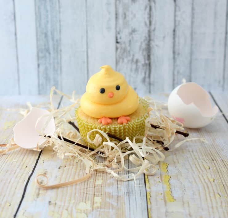 Heavily frosted chick cupcake surrounded by eggshells. 
