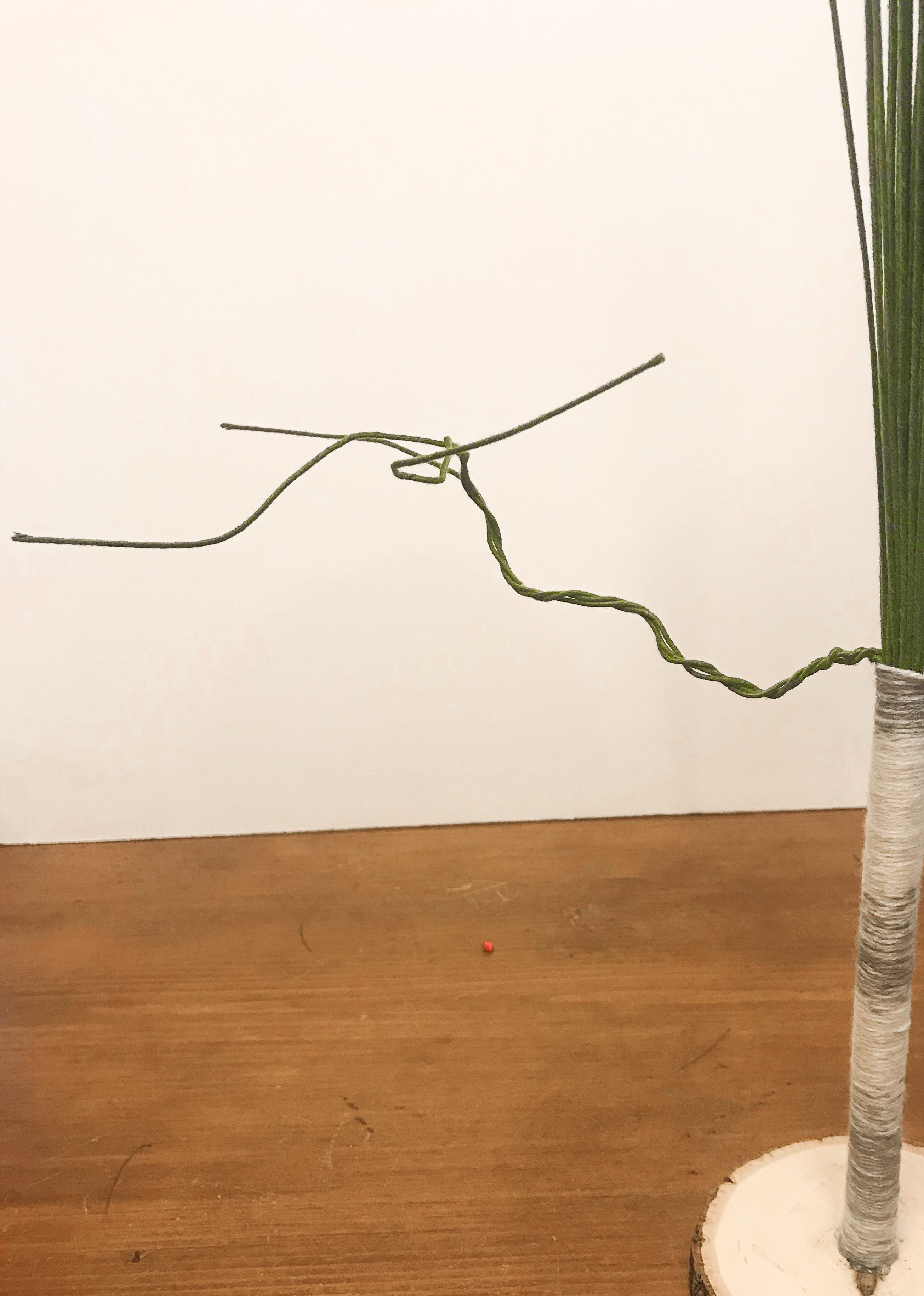 Three floral stems twisted away from yarn wrapped trunk and bent to form branches.