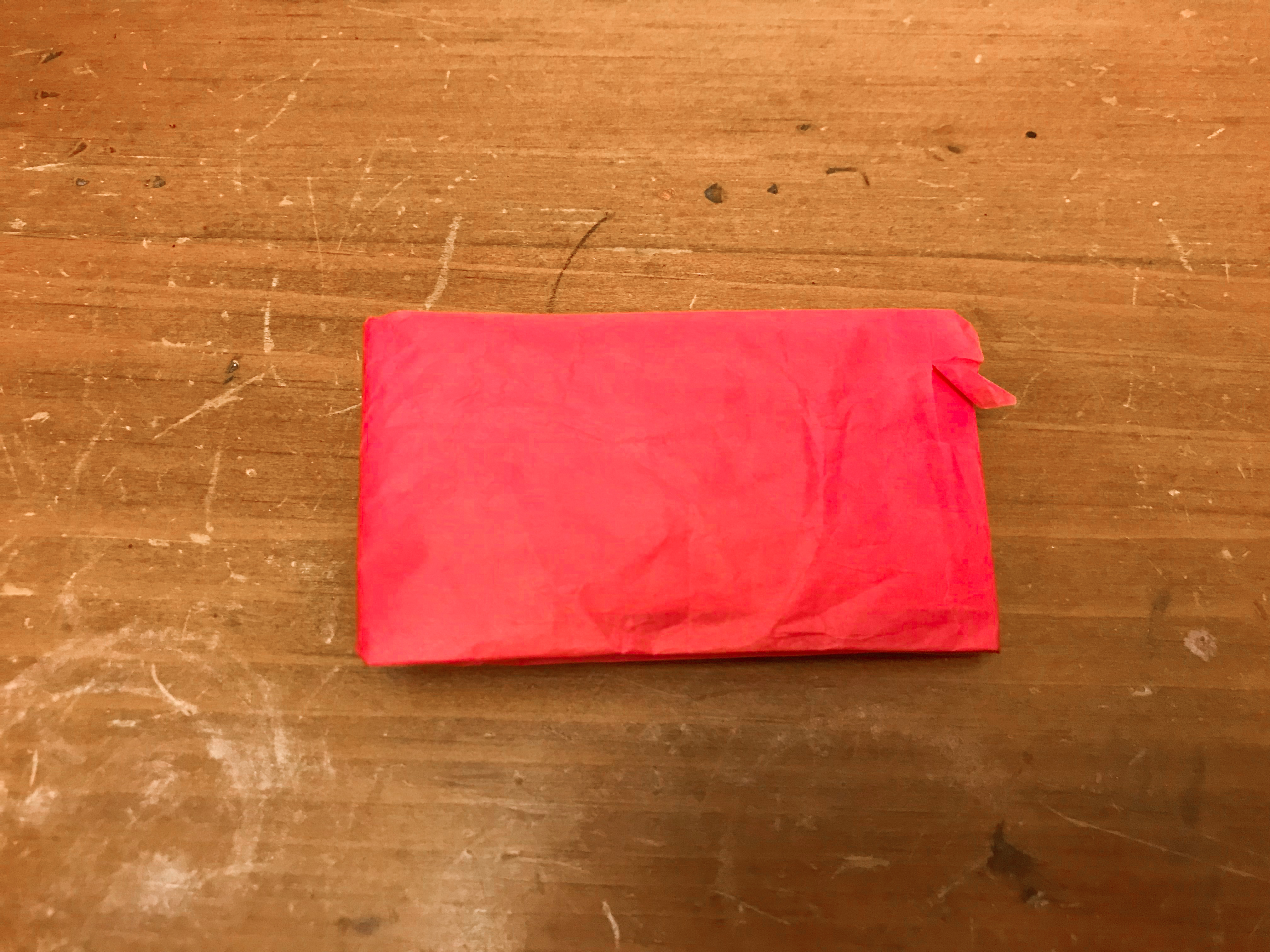 Folded pink tissue paper on wood background
