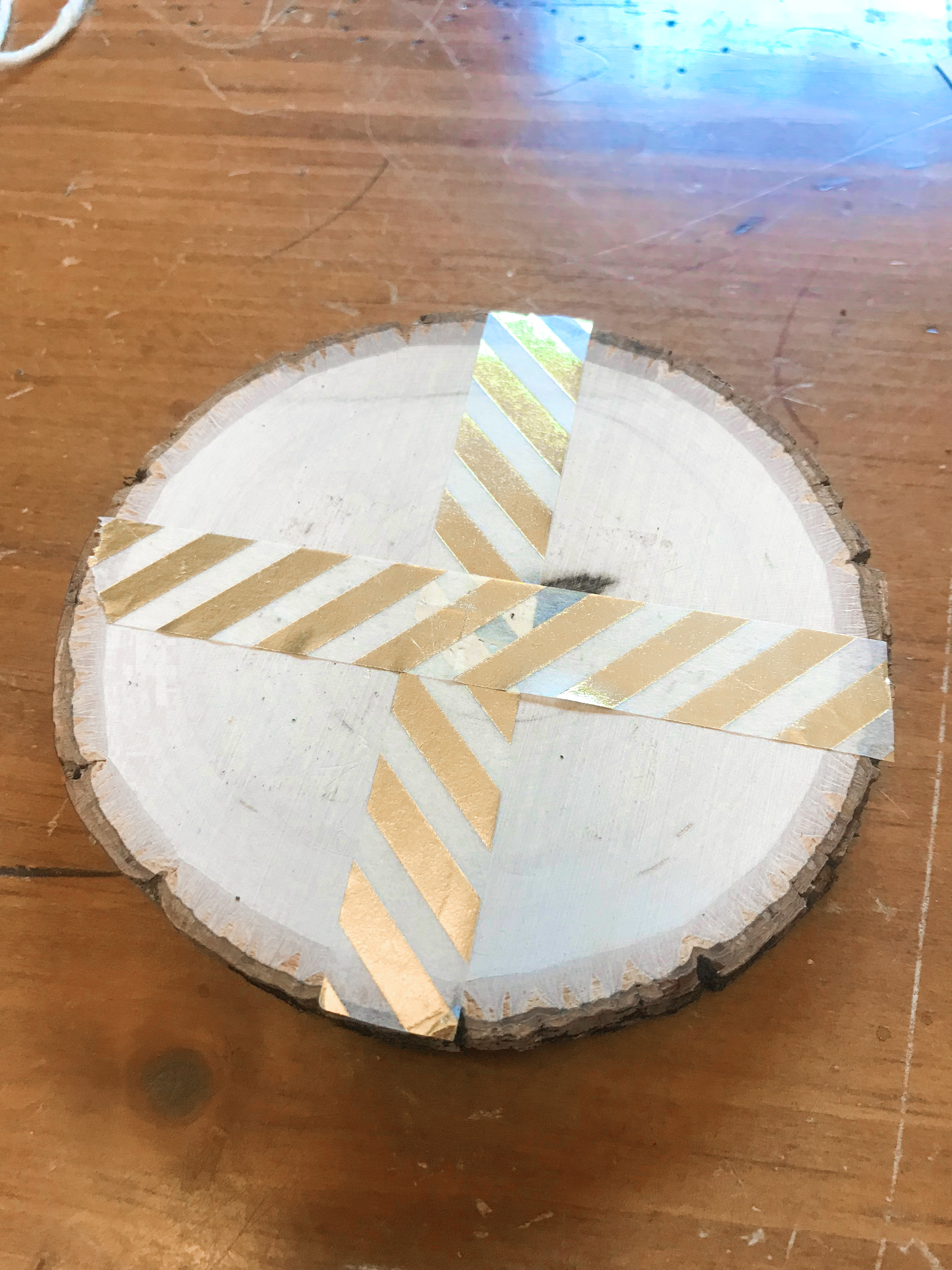 Round wood slice with gold washi tape cross on a wood background
