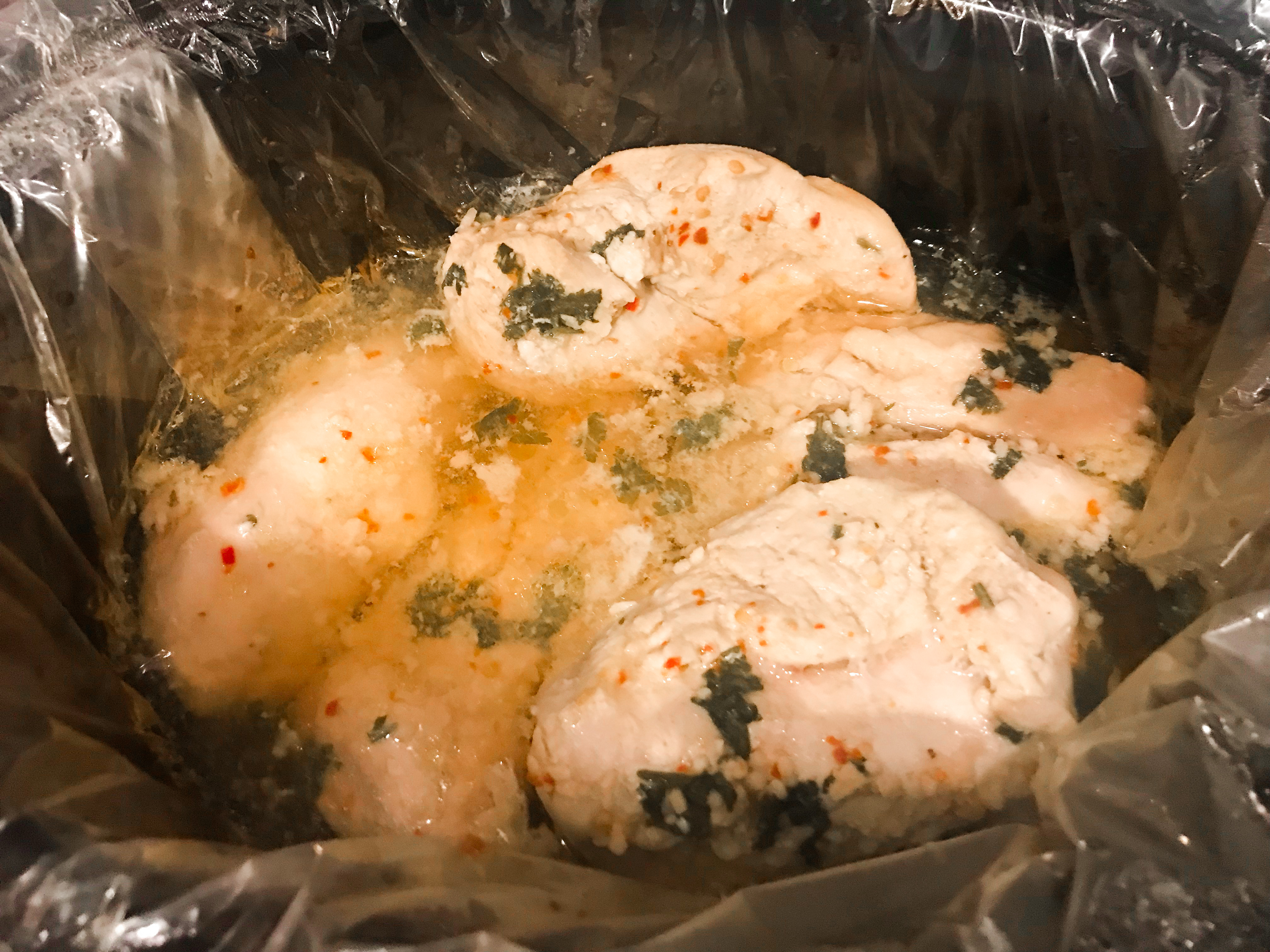 Cooked chicken and seasonings in a lined crockpot. 
