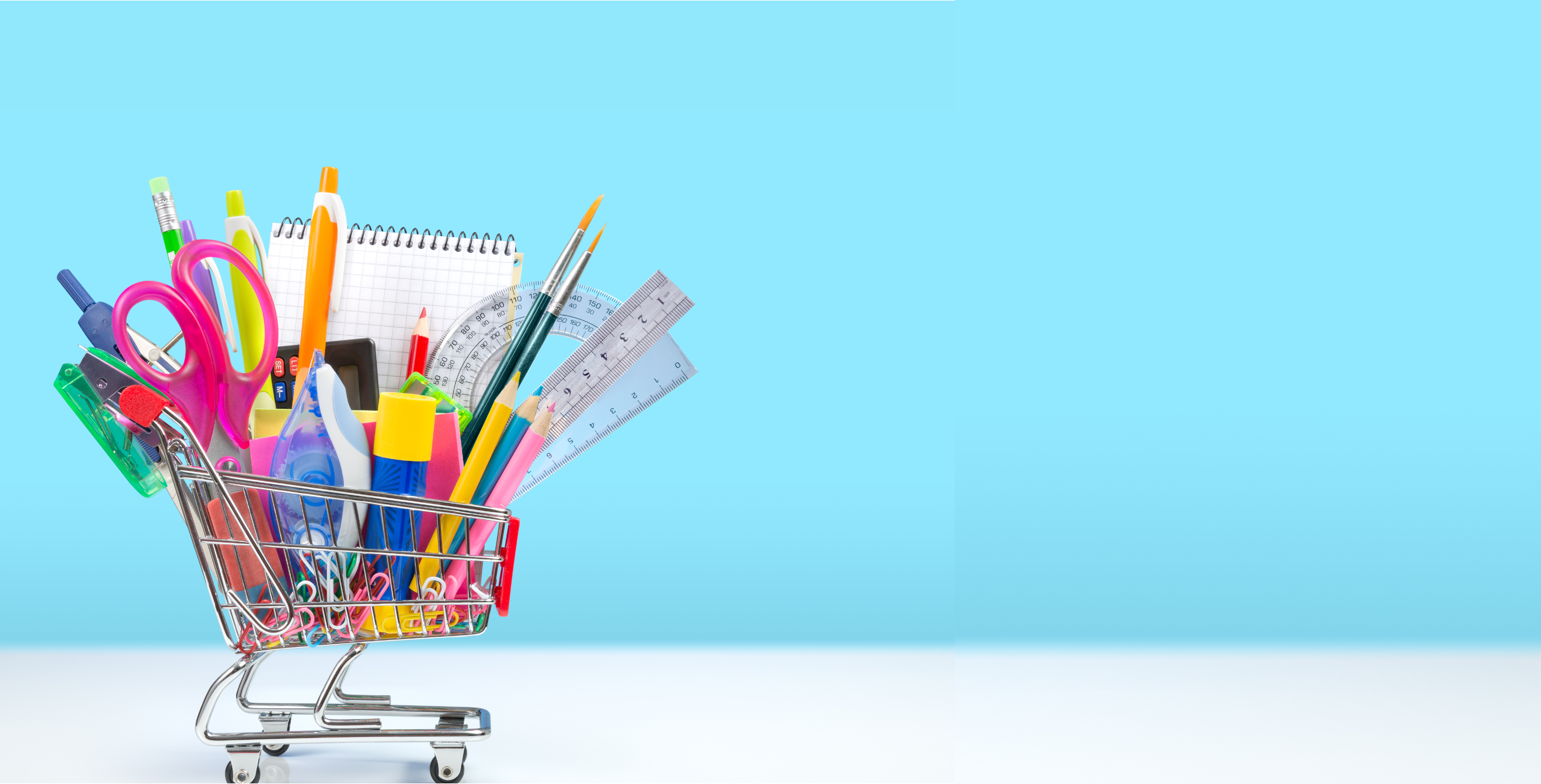 A mini shopping cart filled with school supplies against a blue background.